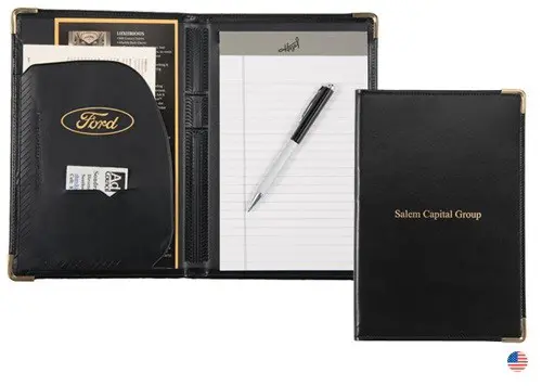 A black folder with a pen and note pad on it.