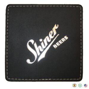 A black leather coaster with the name shiner beers on it.